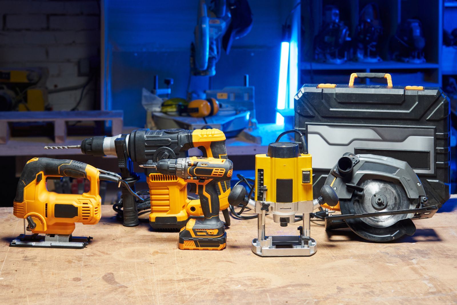 Variety of power tools arranged on a wooden workbench in a workshop, featuring a drill, jigsaw, circular saw, and more, highlighting versatility and utility for DIY projects.