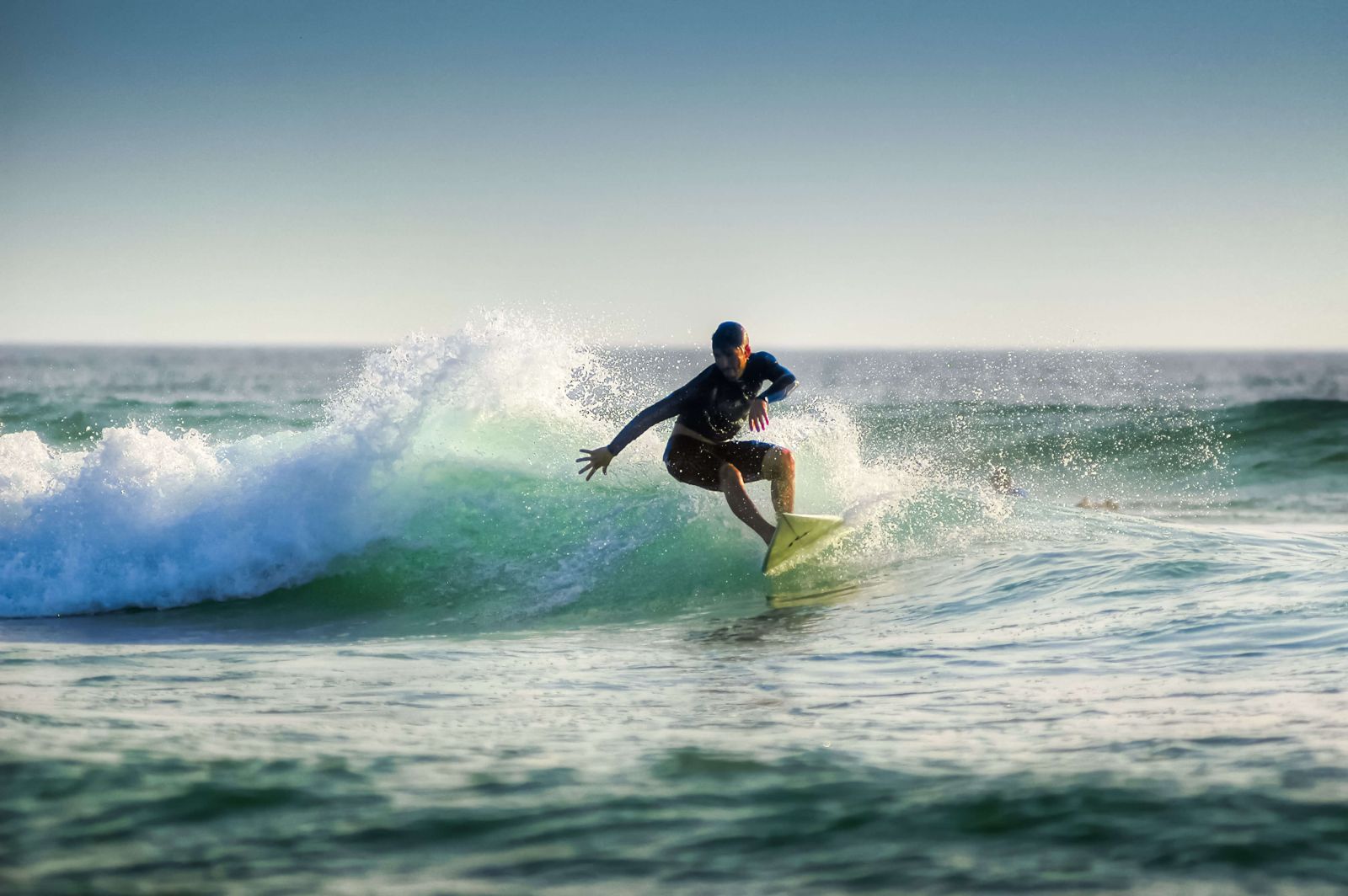 A surfer expertly rides a wave. “Why do surfers wax their surfboards?” — to maintain grip and stability.
